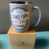 Gray mug with a faith message sitting on a cardboard box