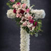 A foam cross filled with white flowers, lined with greenery.  Red