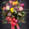 A vase arrangement filled with greenery and assorted colors of roses. (12