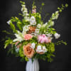 Peach roses and trumpet lilies rise in a tall, garden-inspired arrangement that