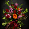 Deep, velvety red roses pair with bright orange gerbera daisies and soft