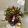 Mixed bouquet with pink roses, tulips, and berries in a gift box