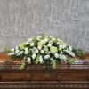 A low, broad casket spray crafted to convey calm and reverence-this funeral