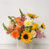 Mixed bouquet of orange, yellow, pink, and white flowers in a patterned vase