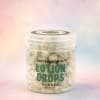 Jar of lotion drops with a pastel background