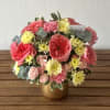 A cheerful garden-style arrangement filled with layers of soft pinks, buttery creams