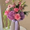 Pink and purple bouquet in a textured vase with a lavender ribbon