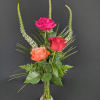 Three roses in a small glass vase with tall green spikes