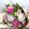 Hand-tied bouquet of pink peonies and cream roses wrapped in kraft paper
