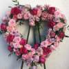 Heart shaped spray is made with pink and lavender blooms. Can be
