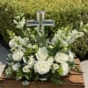 White floral arrangement with a clear cross centerpiece in a wooden box