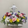 Mixed floral arrangement with a white religious statue centerpiece