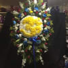 Large standing floral wreath with a yellow and white center and red, blue, and white flowers