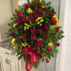 Standing spray of red roses and yellow daisies with a red ribbon