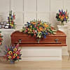 Colorful floral funeral casket spray with standing wreaths and arrangements