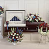 Patriotic funeral floral set with red, white, and blue arrangements around a casket