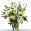 White roses and lilies in a clear glass vase with curly branches
