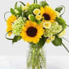 Sunflower bouquet with pale yellow roses in a clear glass vase