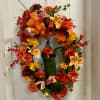 Autumn wreath with orange and red flowers on a white door