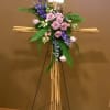 Standing floral cross with pink roses and purple flowers on a bamboo easel