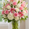 Pink roses and lilies arranged in a clear glass vase