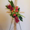 Floral cross arrangement with pink roses and red orchids on a bamboo stand
