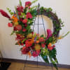 Large floral wreath on a metal stand with red, orange, and pink blooms