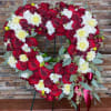 Heart-shaped floral wreath of red roses and white flowers on a stand
