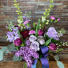 Purple and lavender bouquet in a glass vase with a ribbon