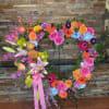Large floral wreath on an easel with pink, orange, yellow, and blue blooms