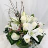 White roses and lilies arranged in a low vase with greenery