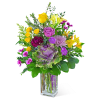 Mixed bouquet of yellow, purple, and pink flowers in a clear glass vase