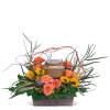 Orange roses and yellow flowers arranged around a bronze urn in a wooden container