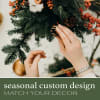 Hands decorating a holiday wreath with pinecones and red berries