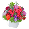 Mixed bouquet of roses and other flowers in a white square vase