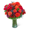 Bouquet of orange and red roses with carnations in a glass vase