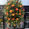 Large standing spray of orange roses with red berries and greenery