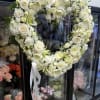 Heart-shaped white floral wreath with a white ribbon bow