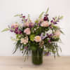 Mixed pink and purple flowers arranged in a glass vase