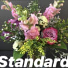 Mixed pink snapdragons and a pink rose with white and yellow accent blooms in a clear vase.
