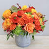Bright orange and yellow flower arrangement in a gray vase