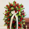 Large red rose funeral spray with white ribbon on an easel