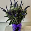 Purple flower arrangement in a glass vase with a ribbon bow