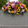 Colorful floral arrangement draped over a gray gravestone