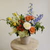 Colorful mixed flower arrangement in a beige vase
