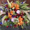 A bold funeral piece with multicolor flowers to remind those of the