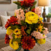 Artificial bouquet of red, yellow, and pink flowers in a black vase