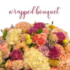 Wrapped bouquet of pink and peach blooms with purple roses and ivory hydrangeas