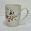 Cream ceramic mug with a bird and floral branch design
