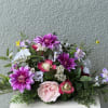 Mixed bouquet of pink, purple, and white flowers in a low arrangement